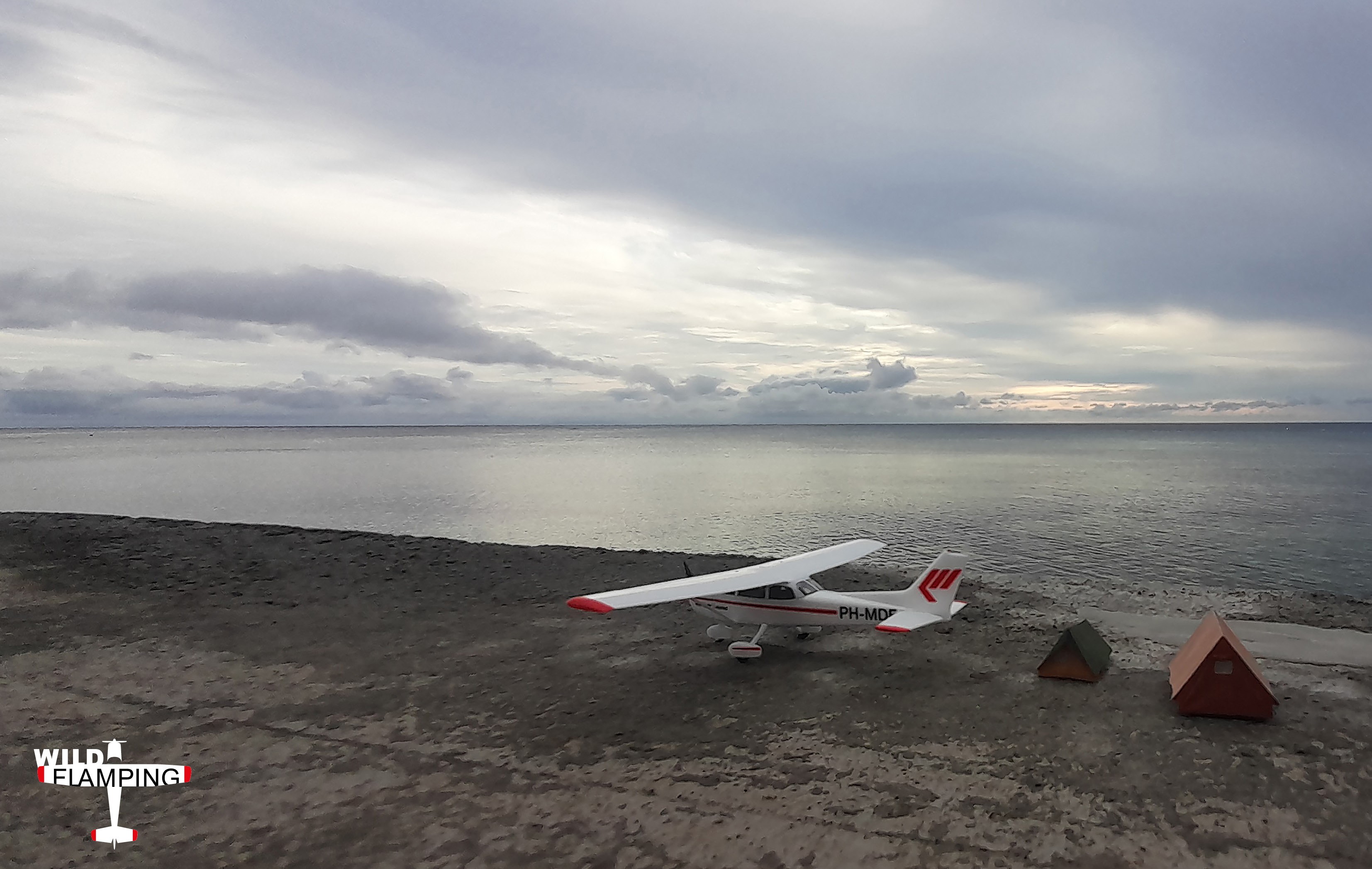 Aircraft parked near tents on a shoreline with dramatic sky